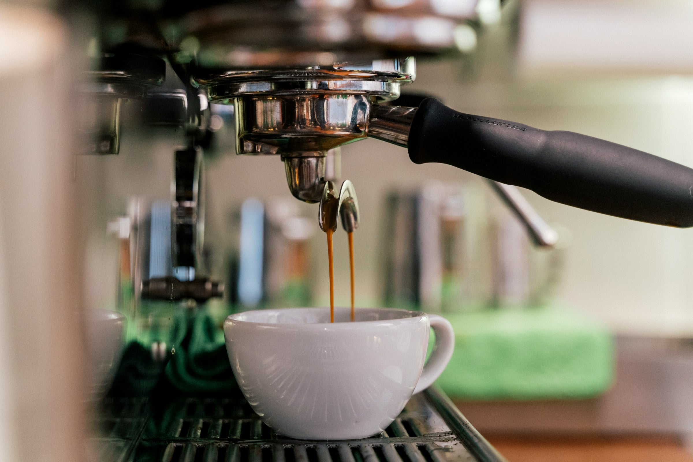 Bild von einem Siebträger in einer Espresso-Maschine auf dem Espresso in eine Tasse läuft.